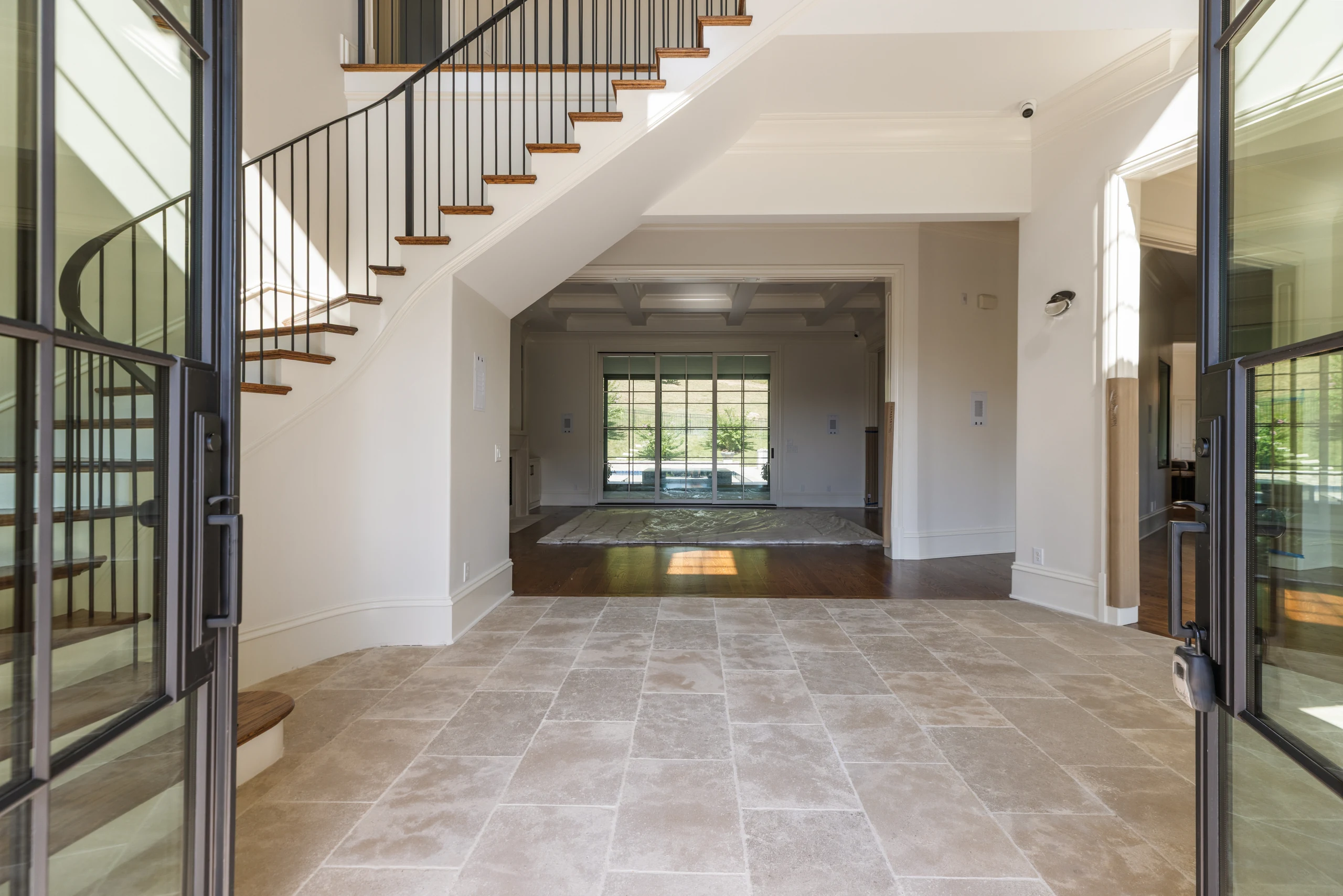 Open iron entry doors framing the limestone foyer and staircase